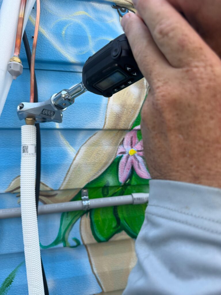 Using an electronic leak detector to inspect the R290 evaporator coil for refrigerant leaks before verifying the flare connection torque.