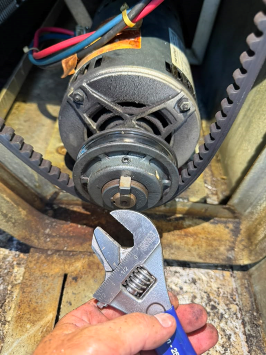 Adjusting the variable-pitch blower sheave to fine-tune blower speed.