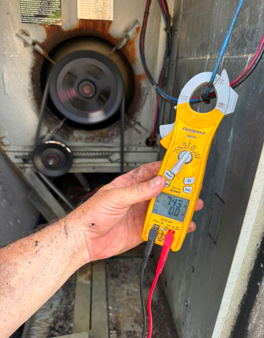 Checking amp draw on the blower motor with a clamp meter to confirm safe operating capacity.