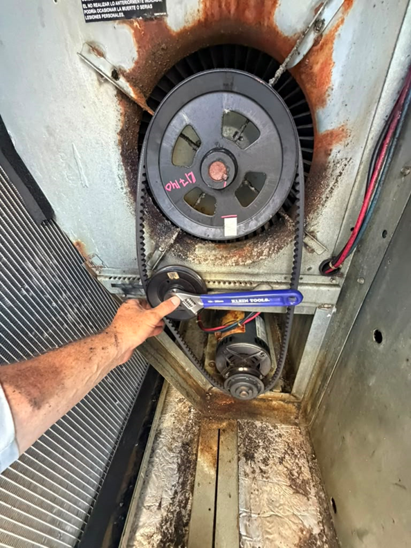 Final adjustment and inspection of the blower pulley and belt drive on the rooftop unit.