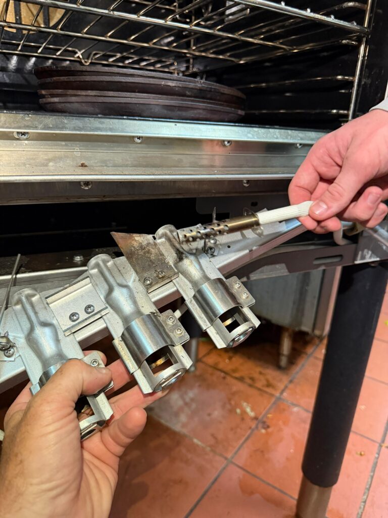 Gas convection oven burner area after hot surface igniter replacement — ready for service