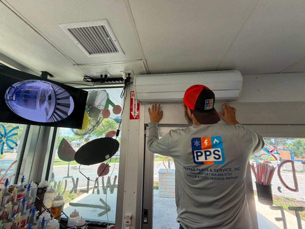 Leveling and securing the air curtain unit above the walk-up window before final wiring and testing.