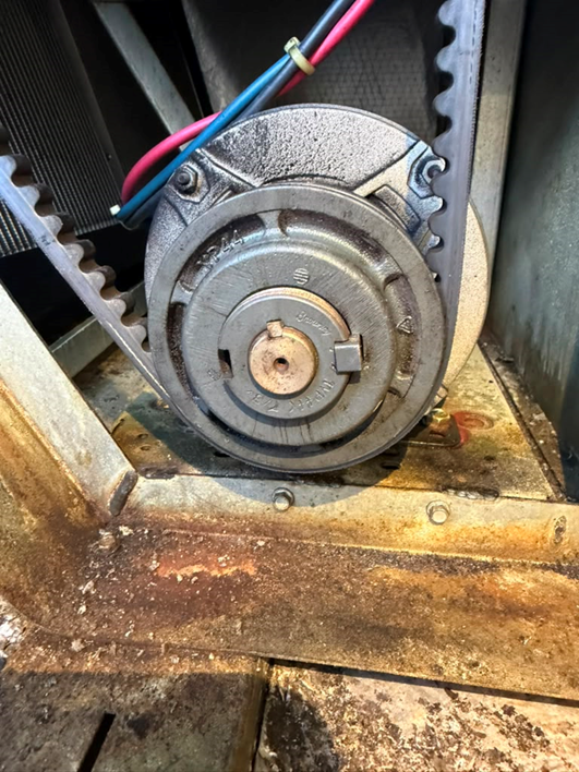 The blower motor and pulley assembly, mounted just below the blower wheel housing.