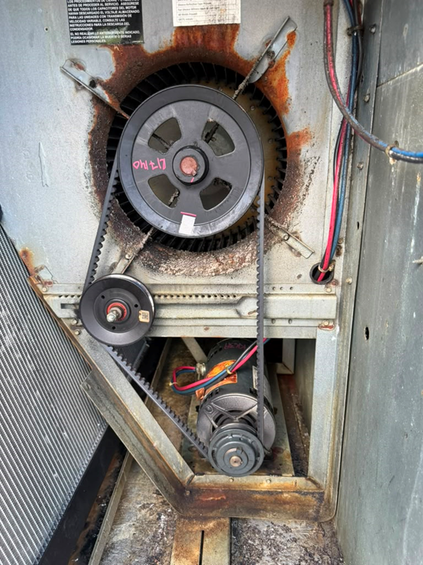 The blower wheel and belt-drive assembly inside the rooftop unit, before any repair work began.