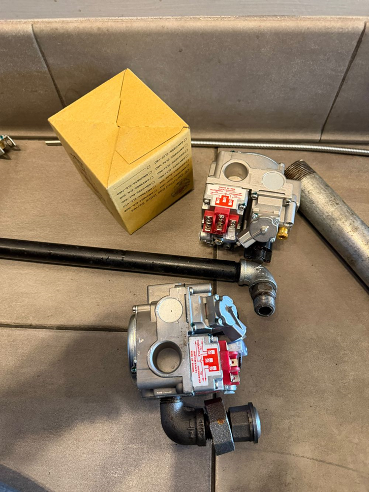 The failed gas valve (bottom) next to its exact-match replacement, confirming port and wiring configuration before installation.