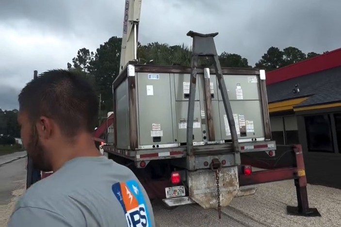 A new rooftop unit arrives on a flatbed and is ready to be rigged for the crane lift.