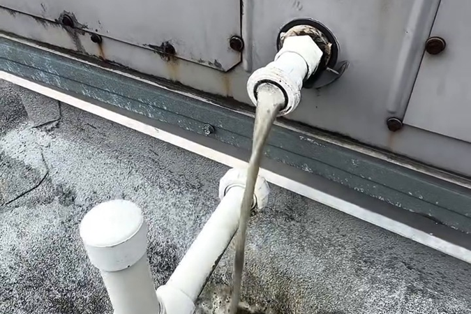 Dark, discolored water flowing from the condensate drain during cleaning.